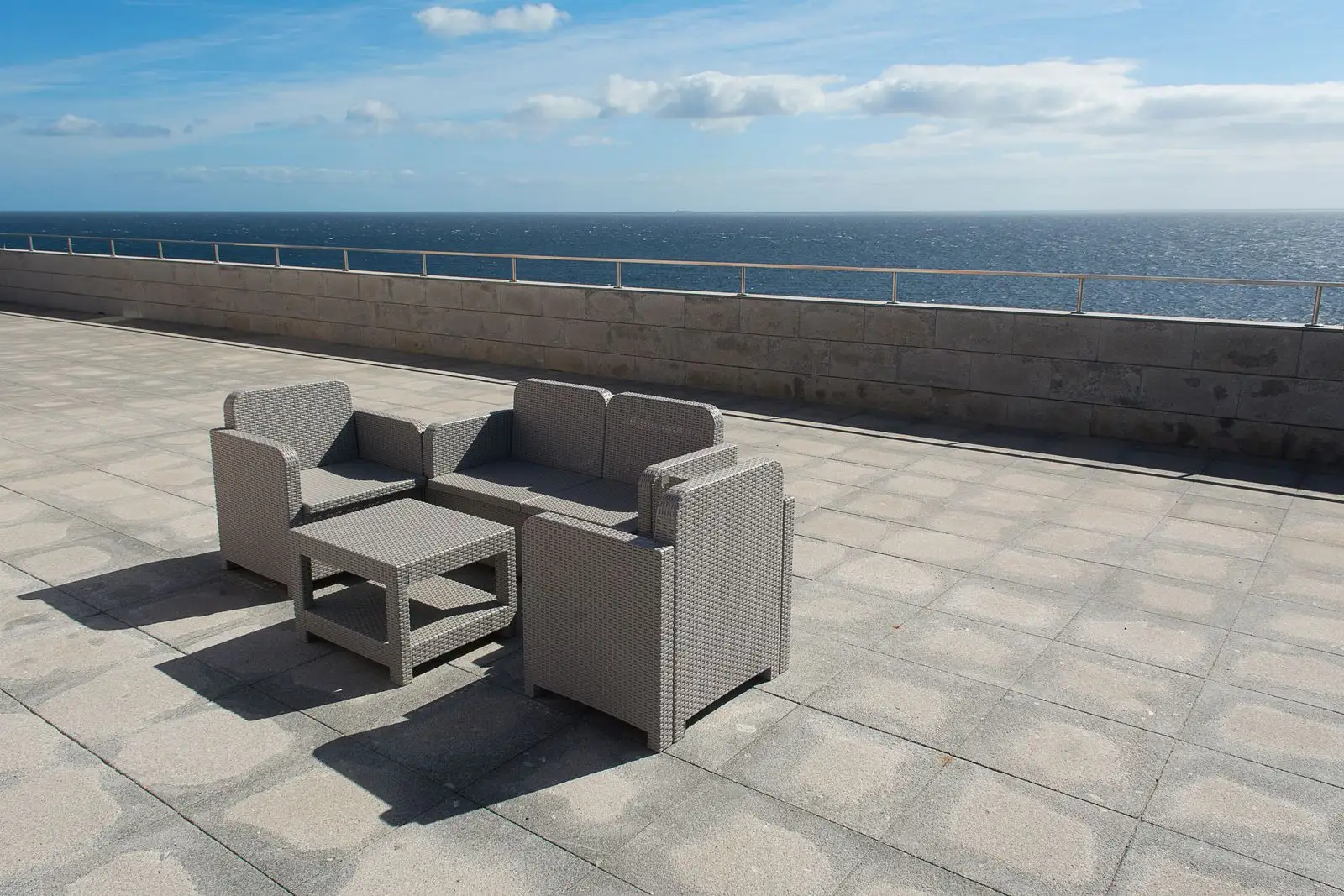 Wicker chairs on a sunny terrace overlooking the open sea — a short-term rental guest’s view