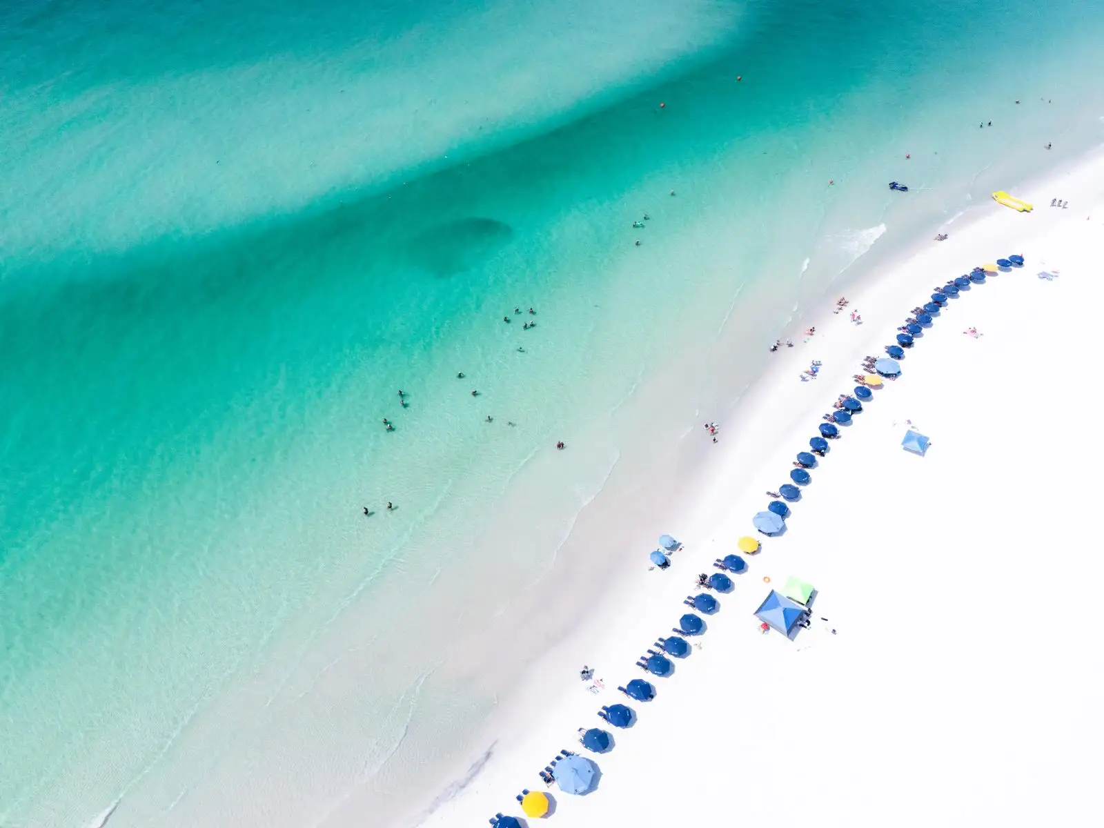 Aerial view of white sand, beach umbrellas and emerald-green water at Santa Rosa Beach