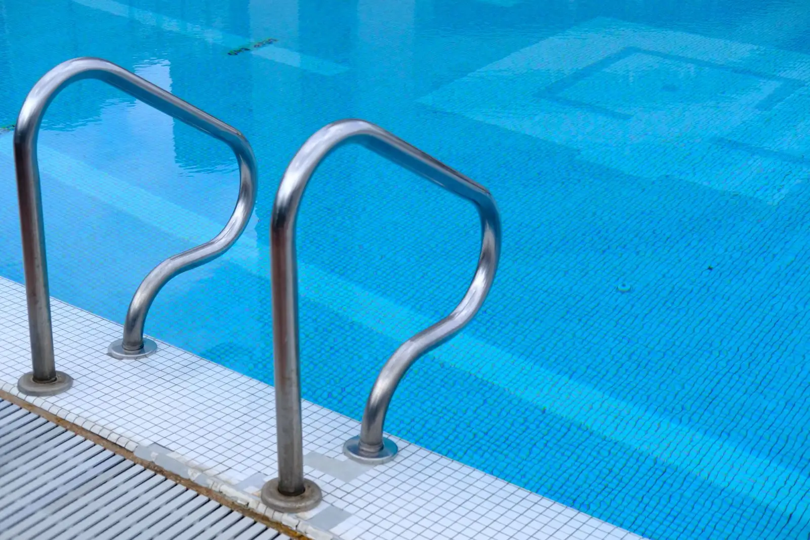 Steel ladder rails in a clean, clear blue pool — rental property pool maintenance