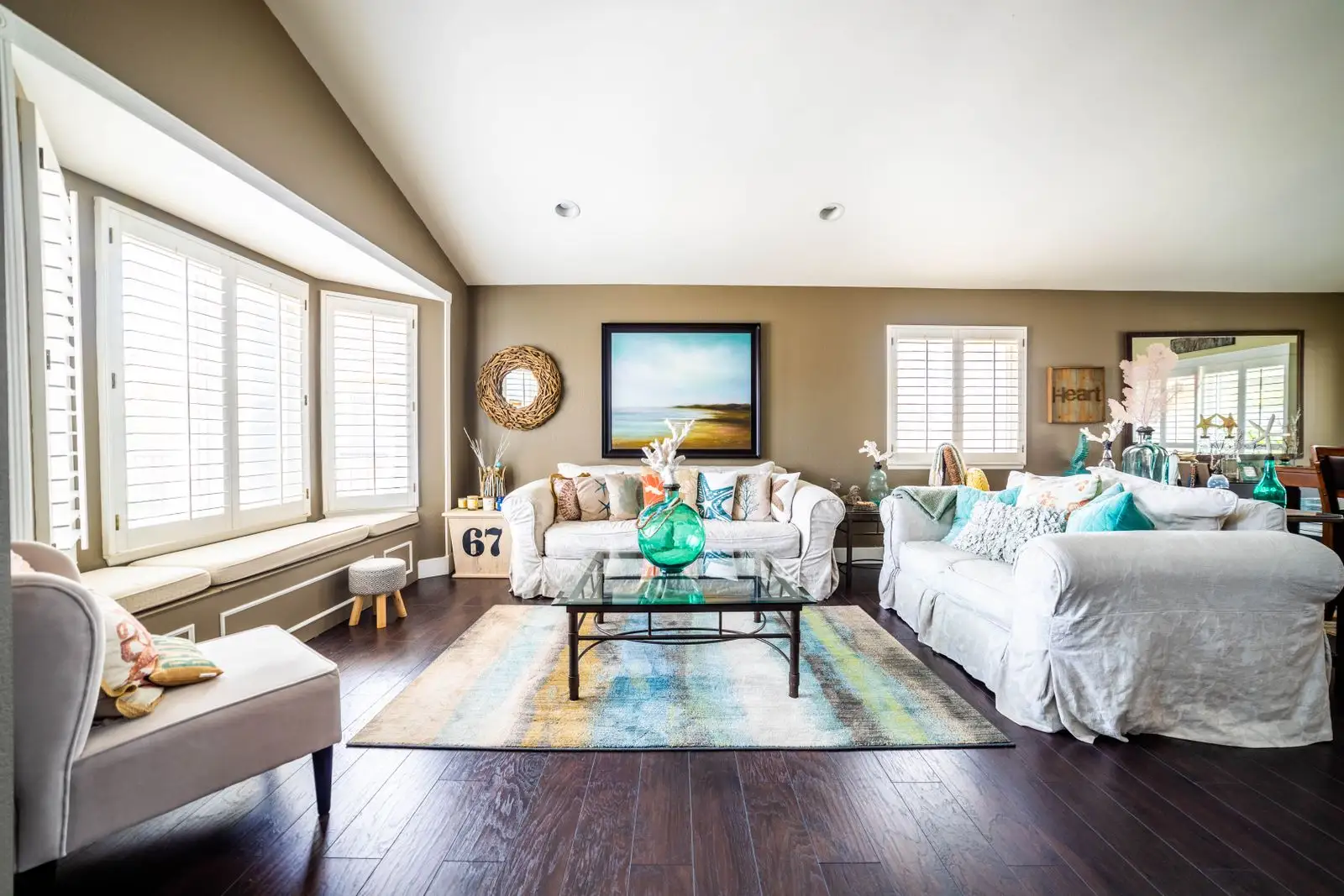 Living room of a vacation rental home with white slipcovered sofas, plantation shutters and coastal decor